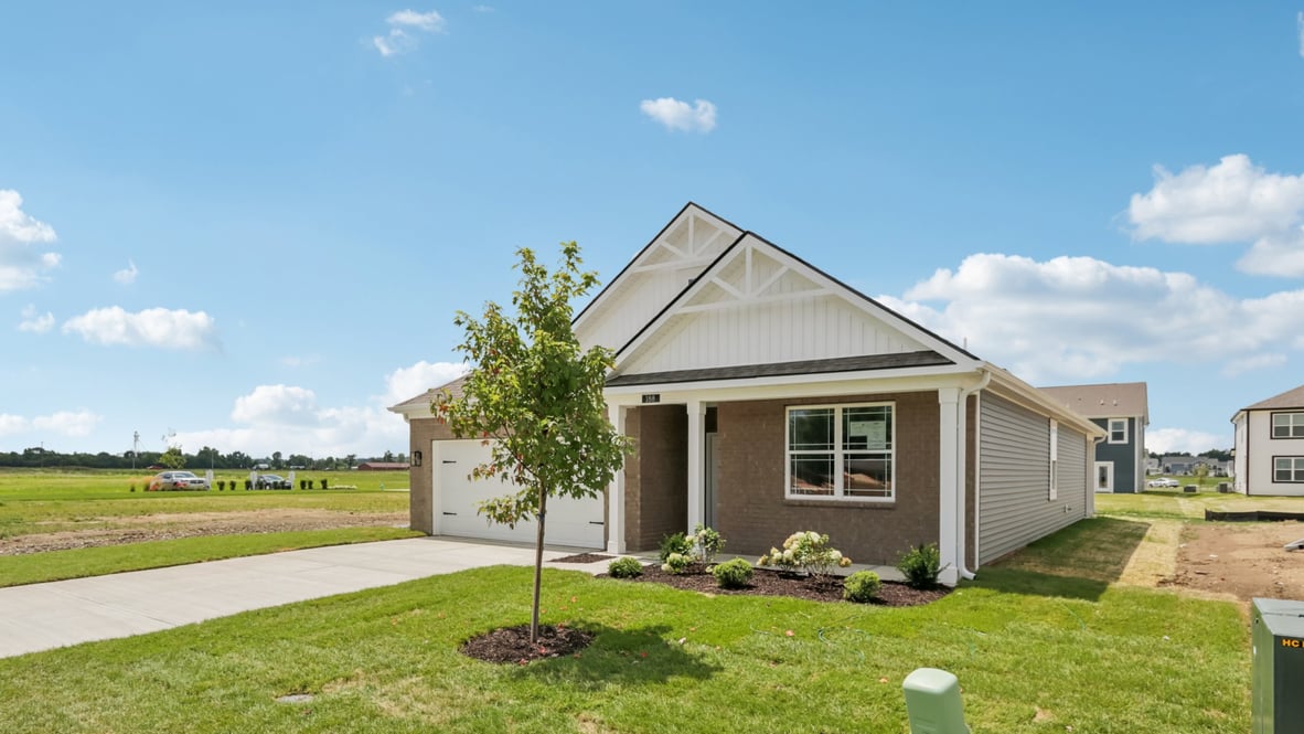 front exterior of a home with grey siding, brick accents and a car garage
