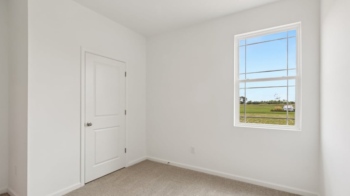 bedroom with brown flooring, white walls and a window