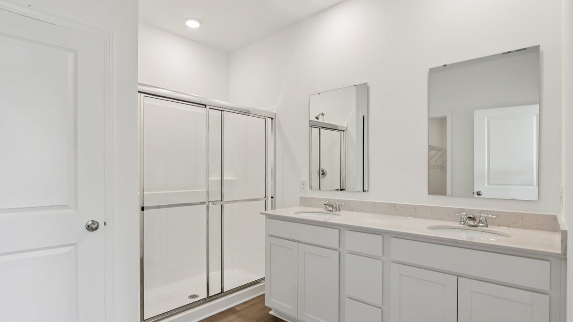 bathroom with dual vanity sinks, toilet, and a walk in shower