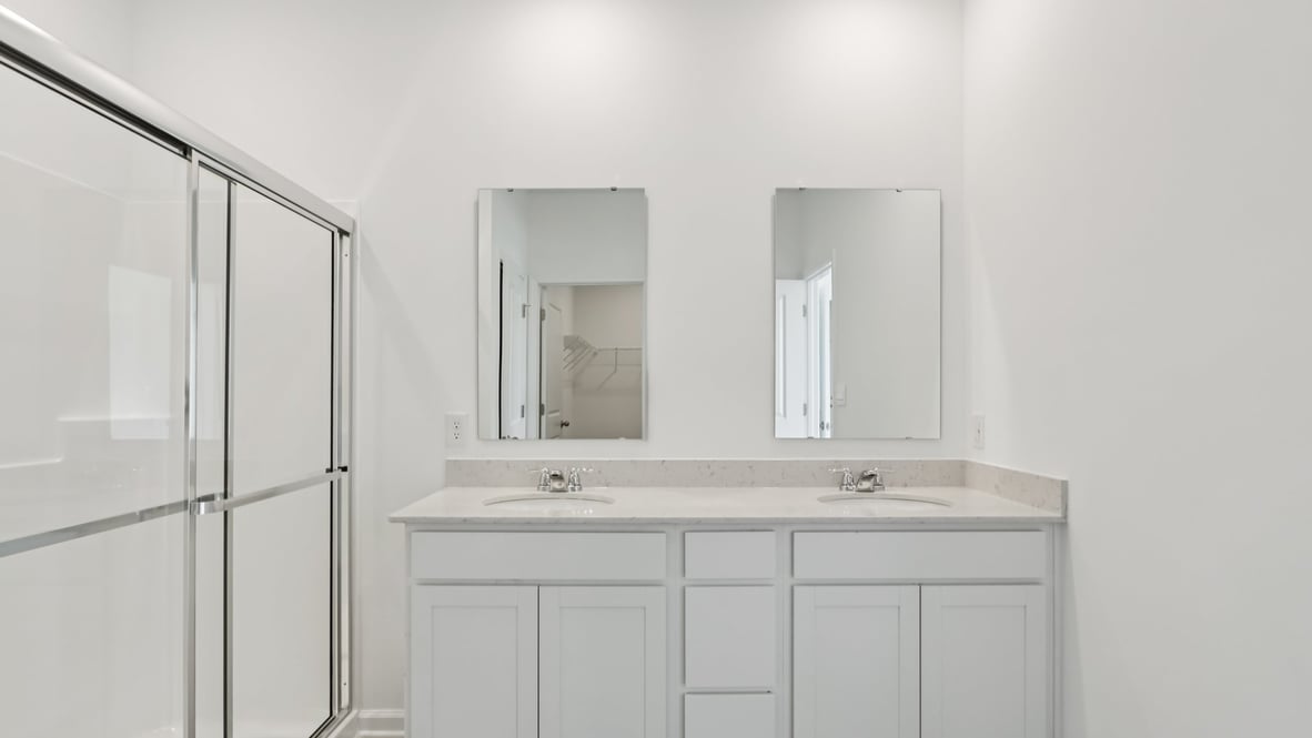 bathroom with dual vanity sinks, toilet, and a walk in shower