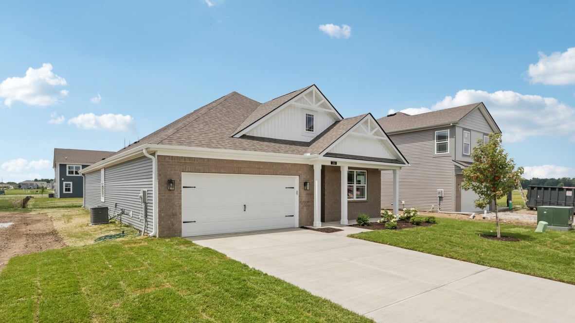 front exterior of a home with grey siding, brick accents and a car garage