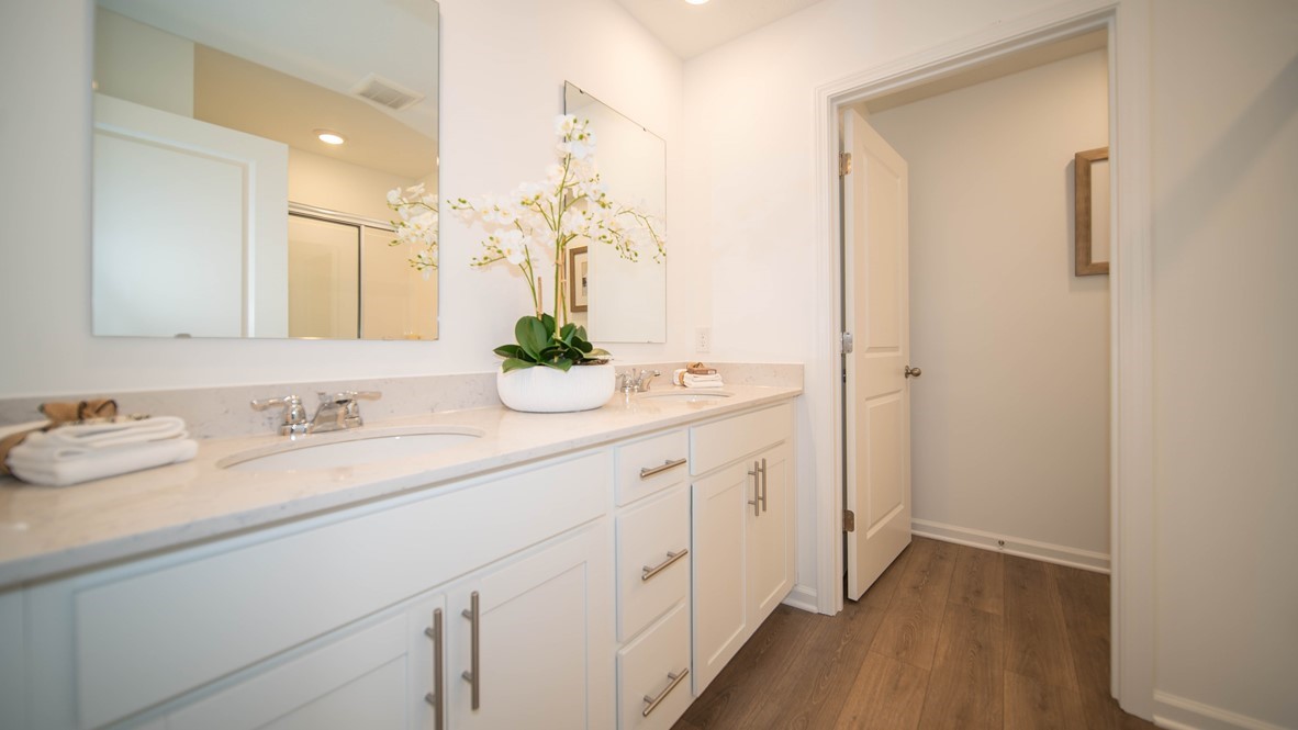 primary bathroom with two sinks white cabinets and quartx counters