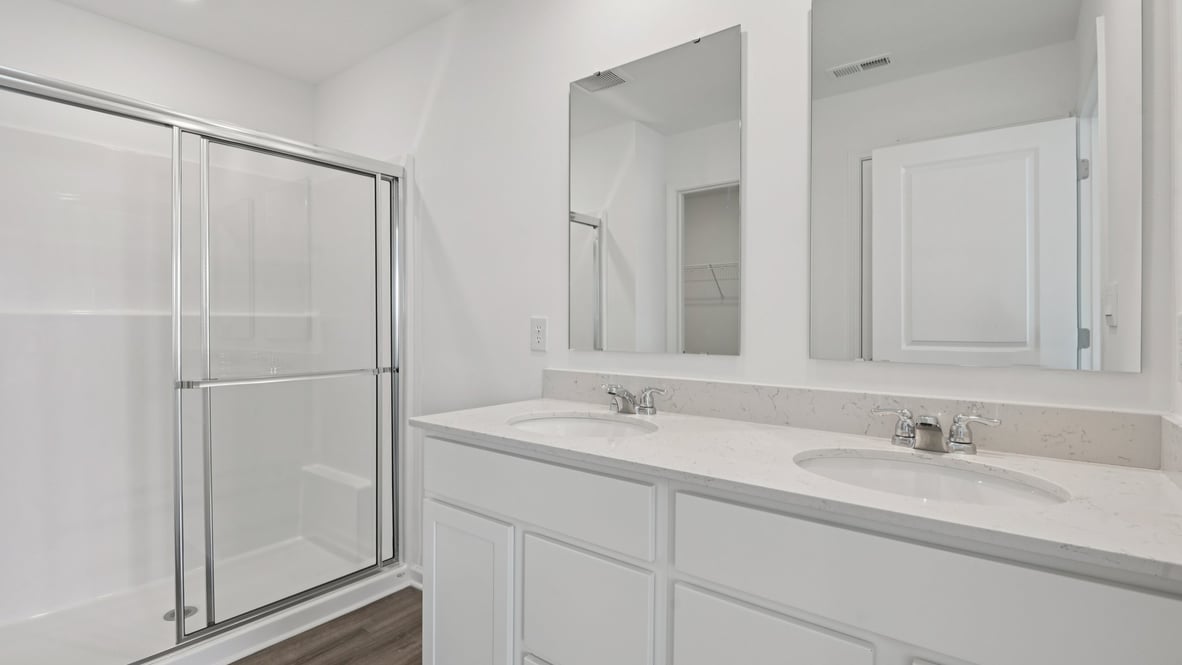 primary bathroom with quartz counters, two sinks and shower