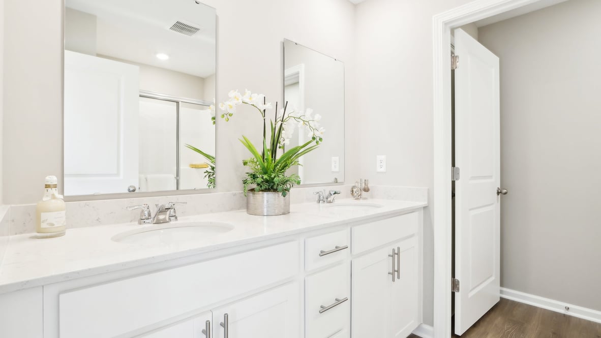 primary bathroom with quartz countertops, white cabinets and two sinks