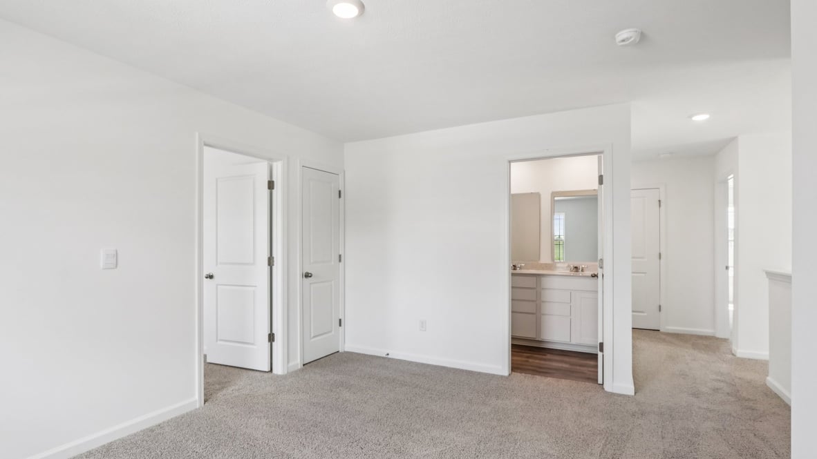 Primary bedroom features ample space, double windows, soft carpet, a stylish walk-in closet, and a private ensuite bath