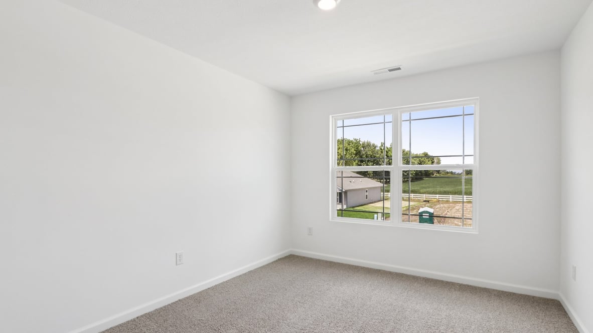 bedroom with beige carpet, white walls and a window