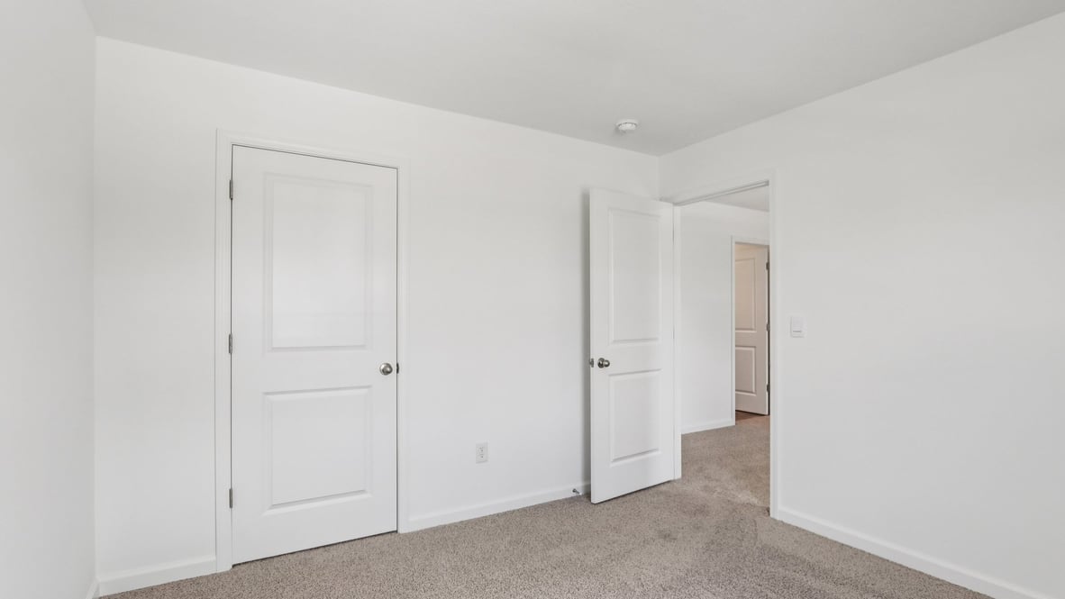 bedroom with beige carpet, white walls and a window