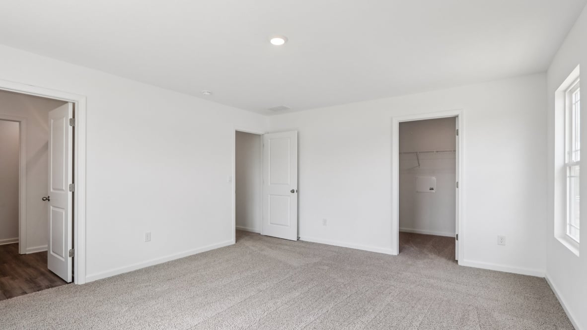 bedroom with beige carpet, white walls and a window