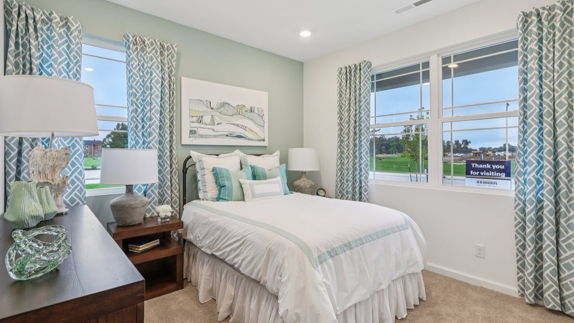 bedroom with twin bed dresser and multiple windows