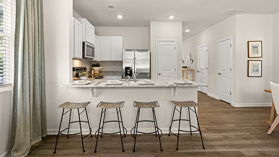 kitchen with quartz countertops, stainless steel appliances and bar seating in townhome