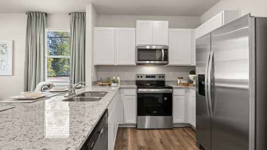 kitchen with quartz countertops, stainless steel appliances and bar seating in townhome