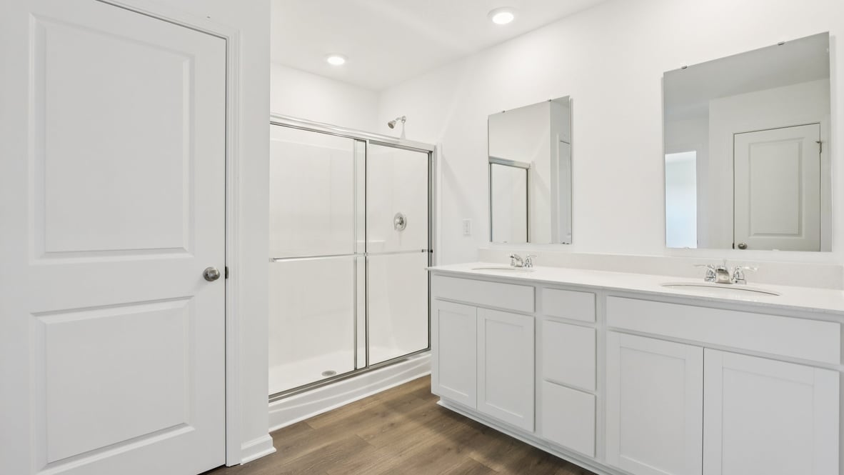 primary bathroom with double vanity and walk in shower