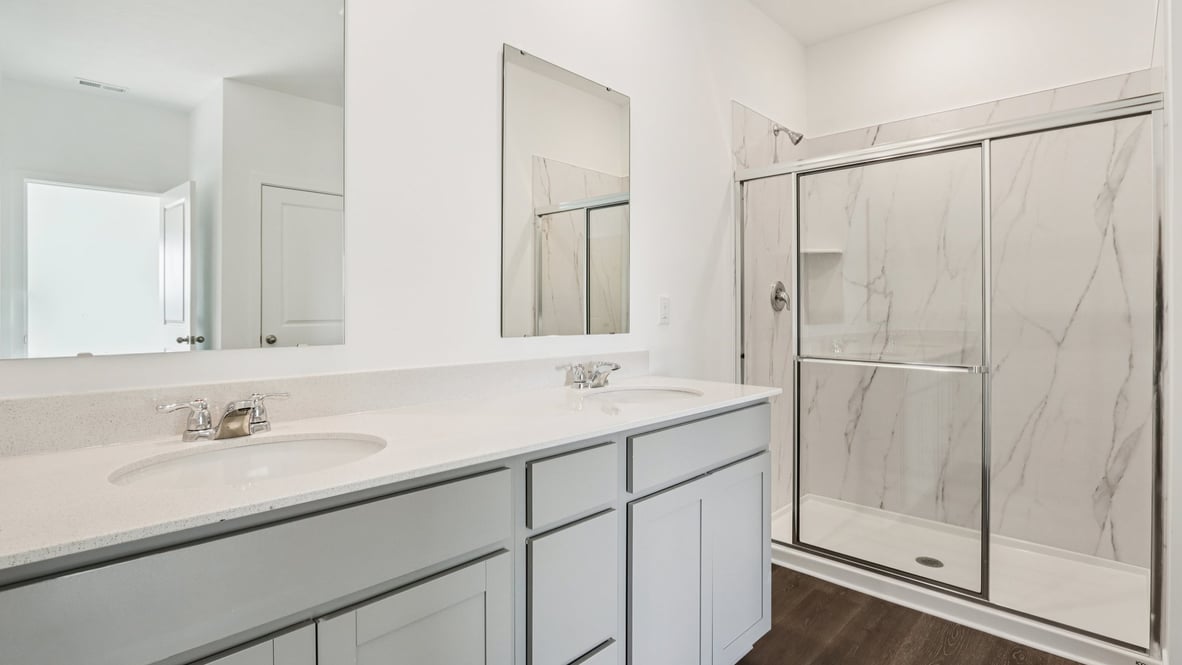 primary bathroom with double vanity and walk in shower