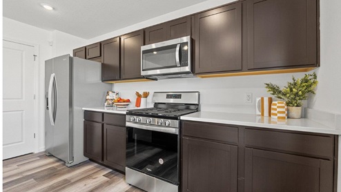 Colonial Height Bellamy model home kitchen with dark cabinets and stainless steel appliances included