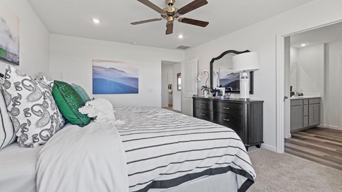 Livingston Lakes Holcombe model home main bedroom with carpet flooring and 52" ceiling fan