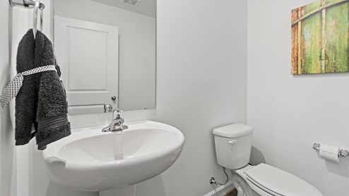 Livingston Lakes Holcombe model home half bathroom with pedestal sink and LVP flooring