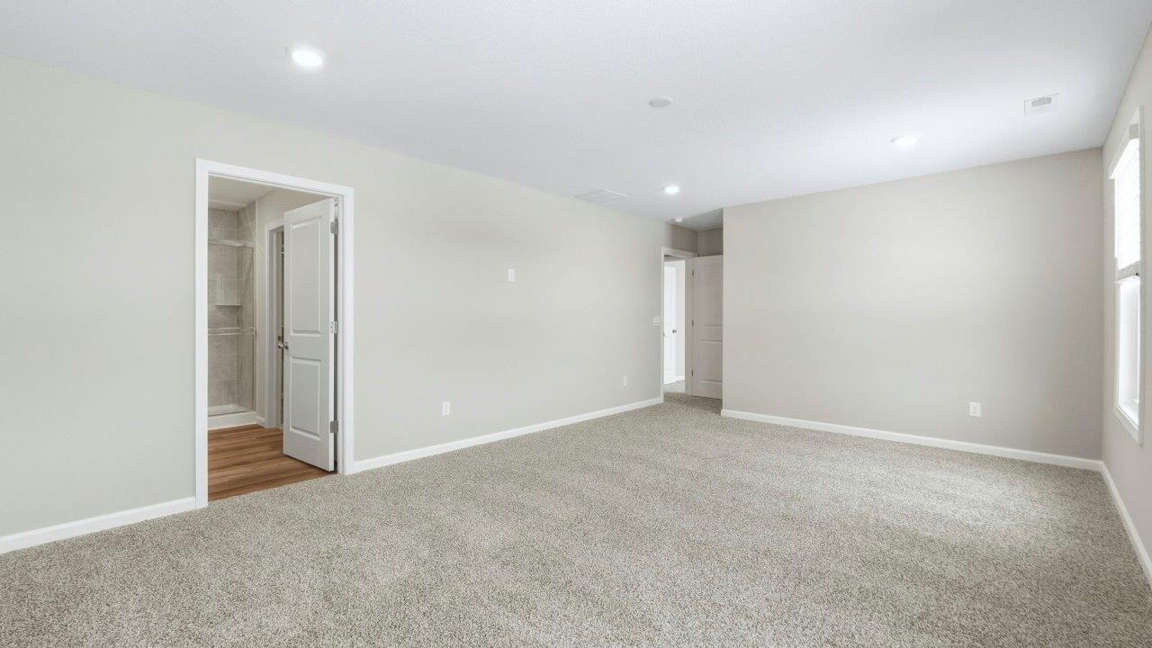 spacious primary bedroom with elk beige carpet, popular grey walls, 2 windows, disc lighting, and ensuite walk-in closet and bathroom