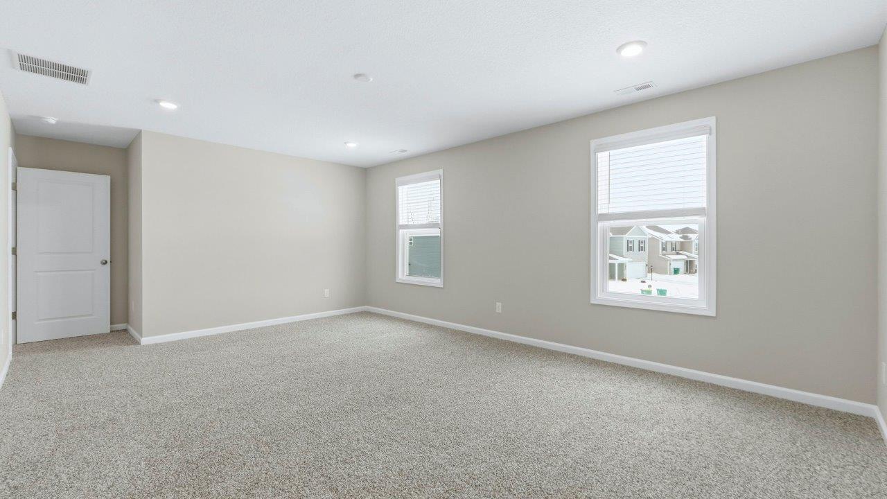 spacious primary bedroom with elk beige carpet, popular grey walls, 2 windows, disc lighting, and ensuite walk-in closet and bathroom