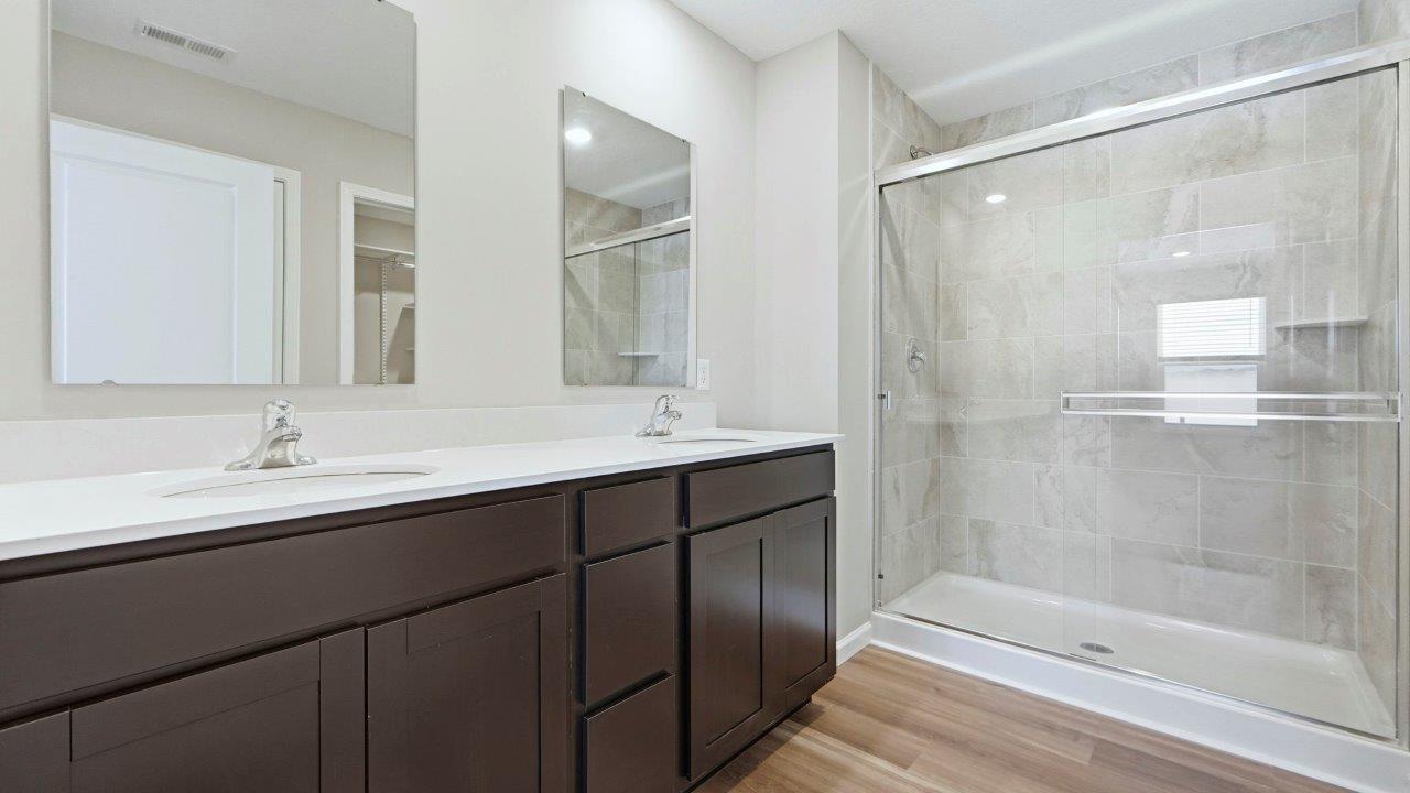 primary ensuite bathroom with sarsaparilla dual sink vanity, lvp flooring, ceramic tile walk-in shower, and private toilet room