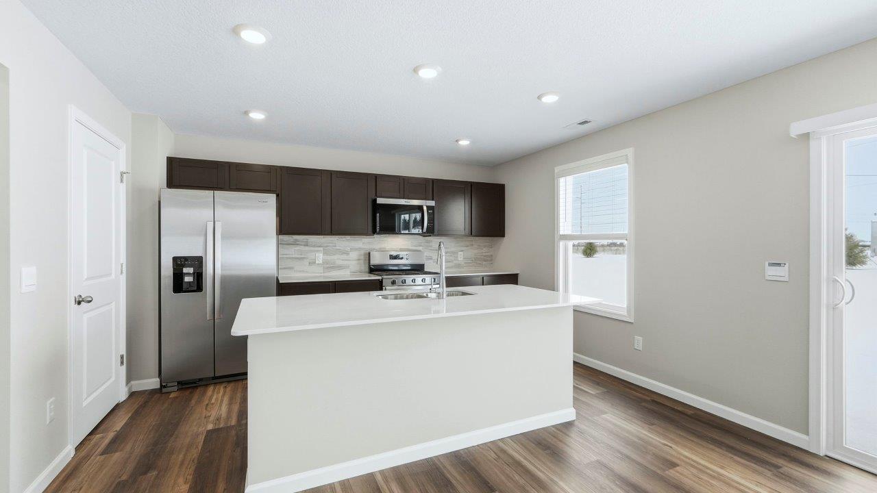 kitchen with sarsaparilla cabinets, quartz counters, stainless steel appliances, tile backsplash, and center island with dishwasher, sink, and bar seating.