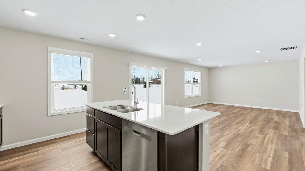 kitchen center island overlooking dining and living room spaces. island includes sarsaparilla cabinets with stainless steel dishwasher and sink.
