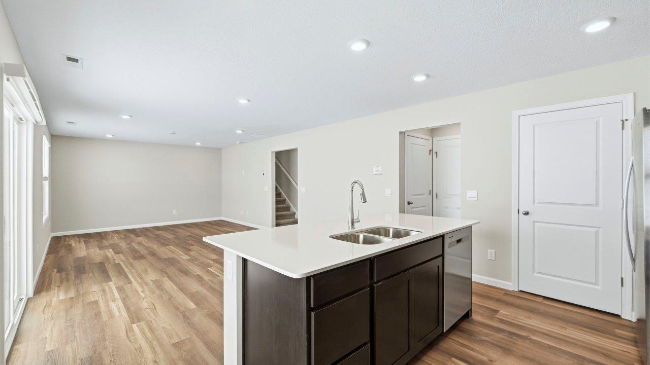 kitchen center island overlooking dining and living room spaces. island includes sarsaparilla cabinets with stainless steel dishwasher and sink.