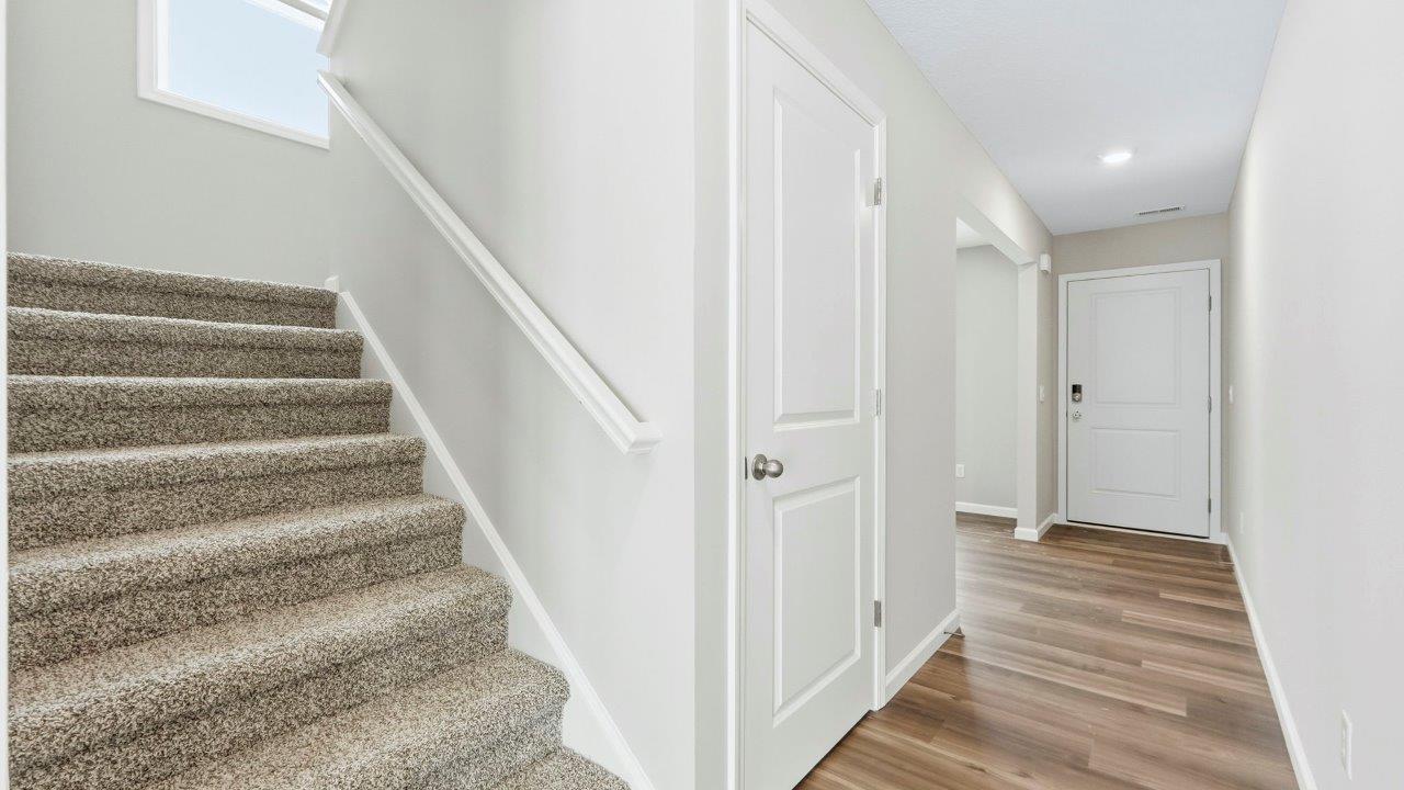half turn staircase to second floor in foyer with elk beige carpet with window