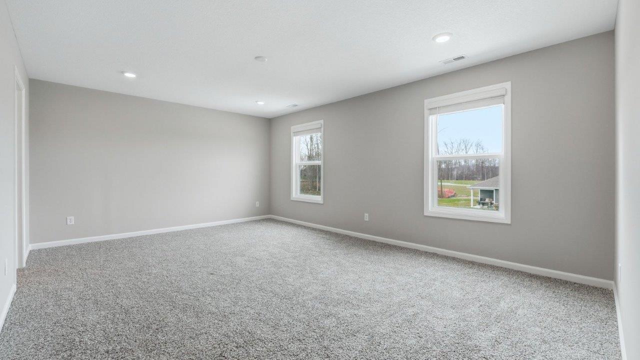 primary bedroom with beige carpet, 2 windows, popular grey walls and ensuite bathroom and walk-in closet