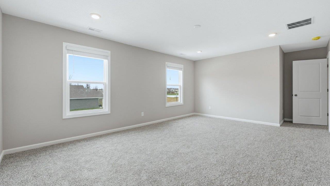 primary bedroom with beige carpet, 2 windows, popular grey walls and ensuite bathroom and walk-in closet