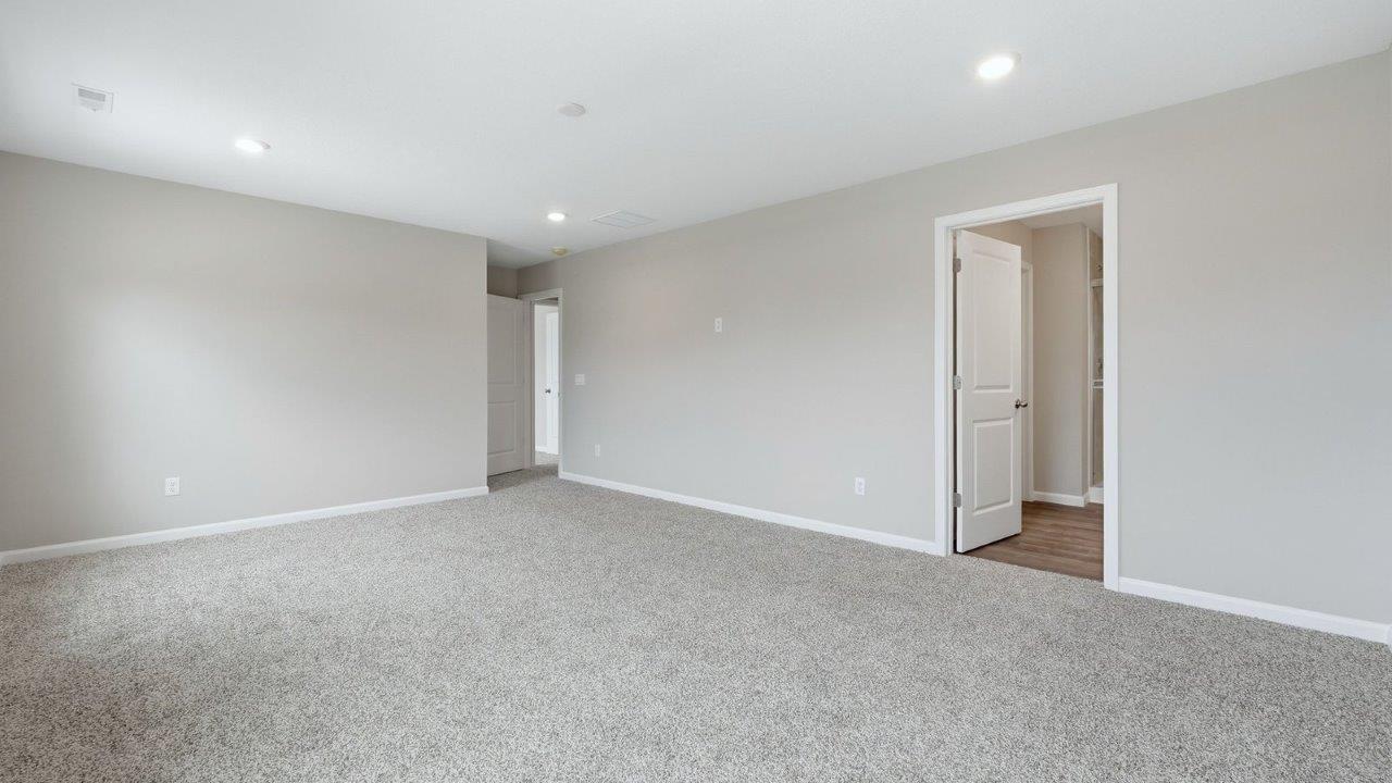 primary bedroom with beige carpet, 2 windows, popular grey walls and ensuite bathroom and walk-in closet