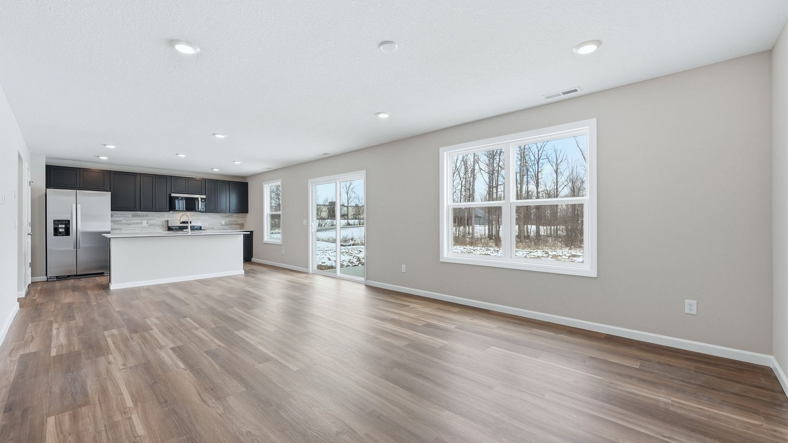 open concept living room with lvp flooring, popular grey walls, 2 windows