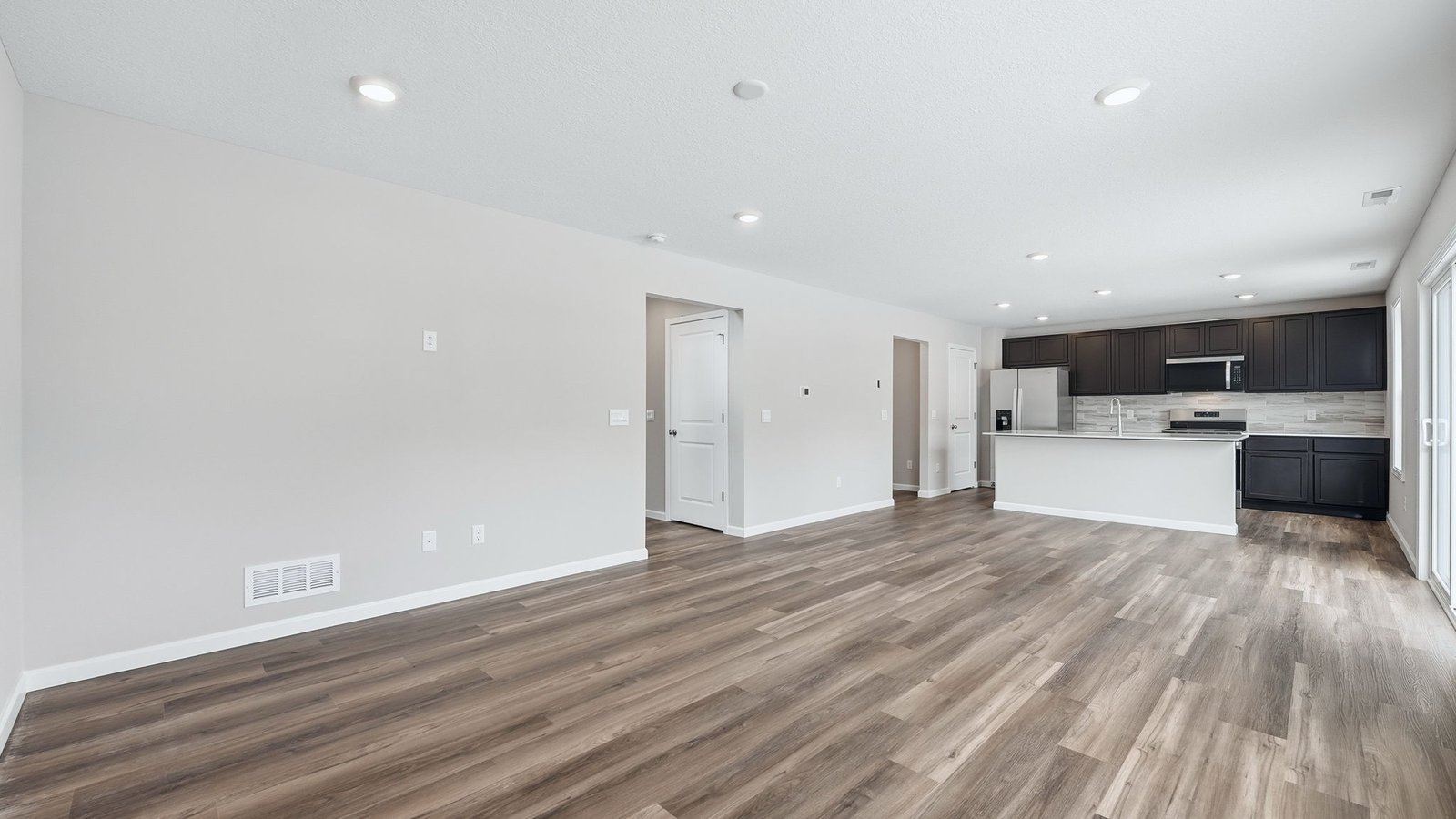 open concept living room with lvp flooring, popular grey walls, 2 windows
