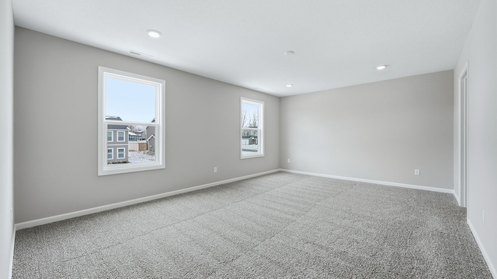 primary bedroom with biege carpet, popular grey walls, 2 windows, and ensuite bathroom and walk-in closet