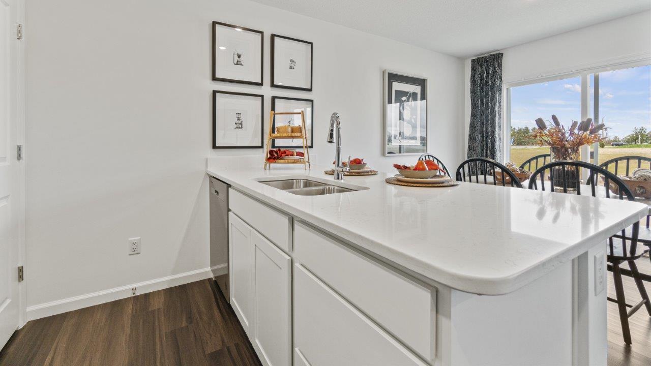 aldridge kitchen with white cabinets, stainless steel appliances, island with seating with quartz counters