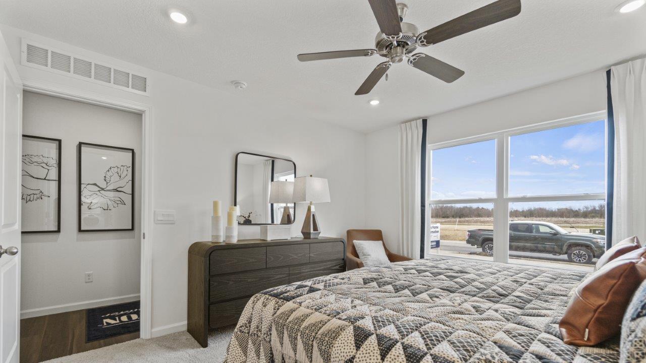 aldridge primary bedroom with carpet, fan, 2 windows, and ensuite bath and closet