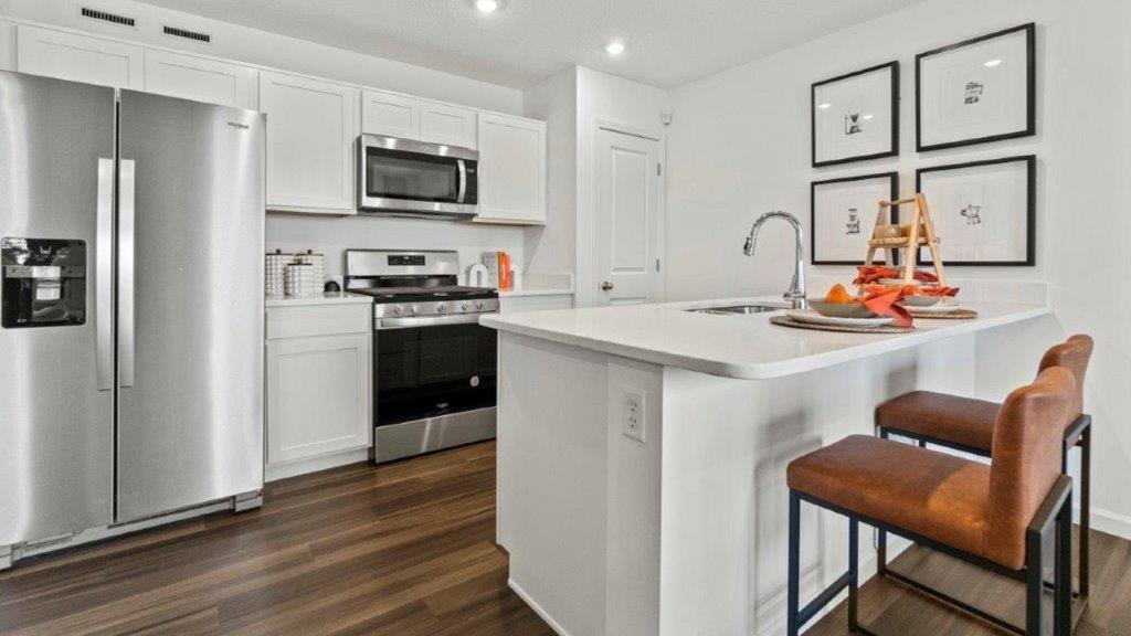 aldridge kitchen with white cabinets, stainless steel appliances, island with seating with quartz counters