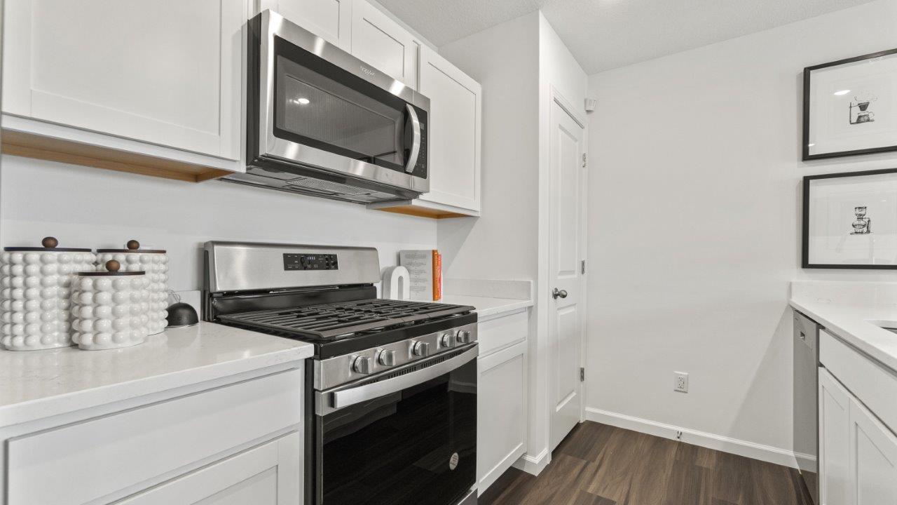 aldridge kitchen with white cabinets, stainless steel appliances, island with seating with quartz counters