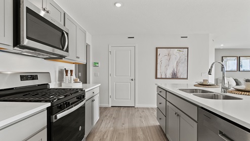 Estates at Signal Ridge Chatham model kitchen with stainless steel appliances including fridge, microwave, oven, stove, dishwasher, and sink