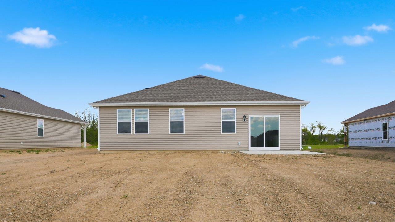 estates at signal ridge harmony villa rear exterior with spacious yard, concrete patio, and pond view