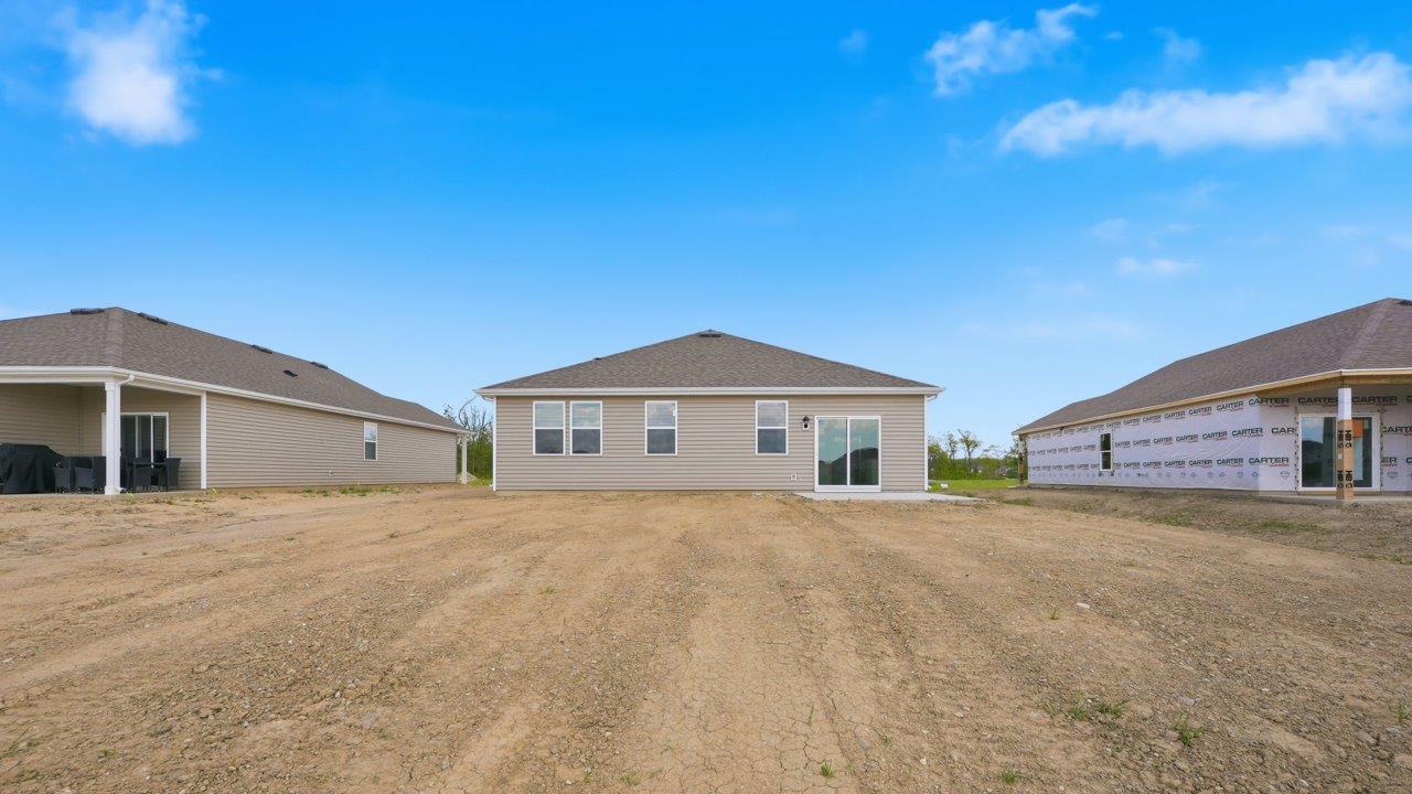 estates at signal ridge harmony villa rear exterior with spacious yard, concrete patio, and pond view
