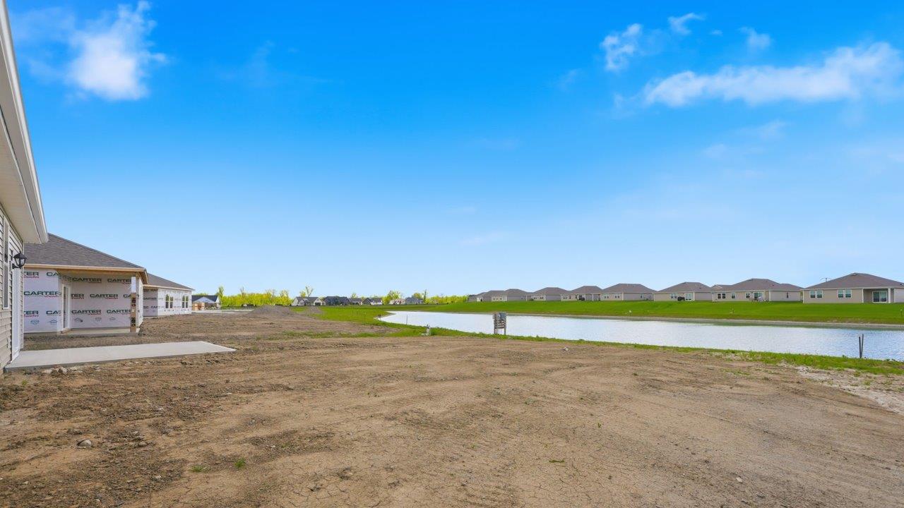 estates at signal ridge harmony villa rear exterior with spacious yard, concrete patio, and pond view