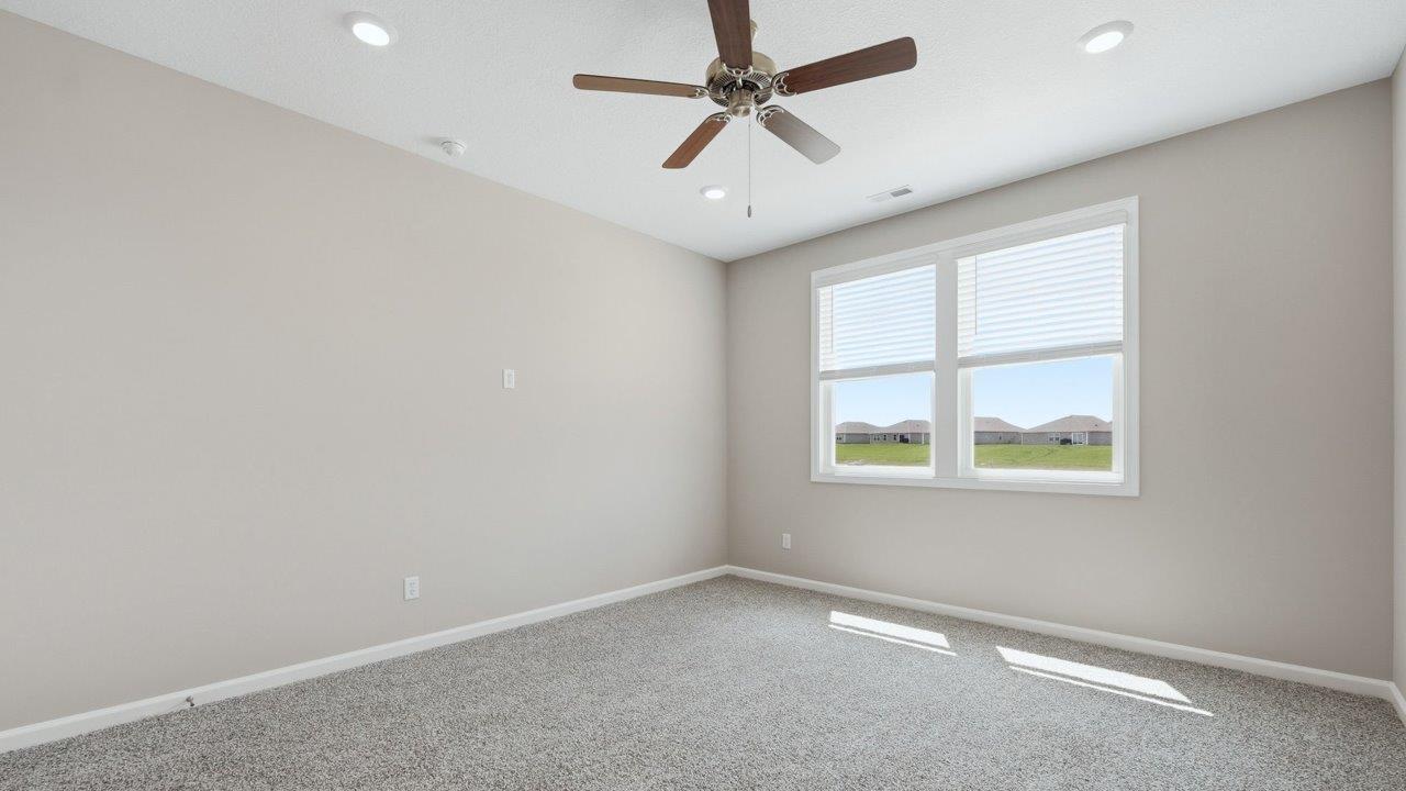 estates at signal ridge harmony villa primary bedroom with 2 windows, carpet, ceiling fan, and ensuite bathroom and closet