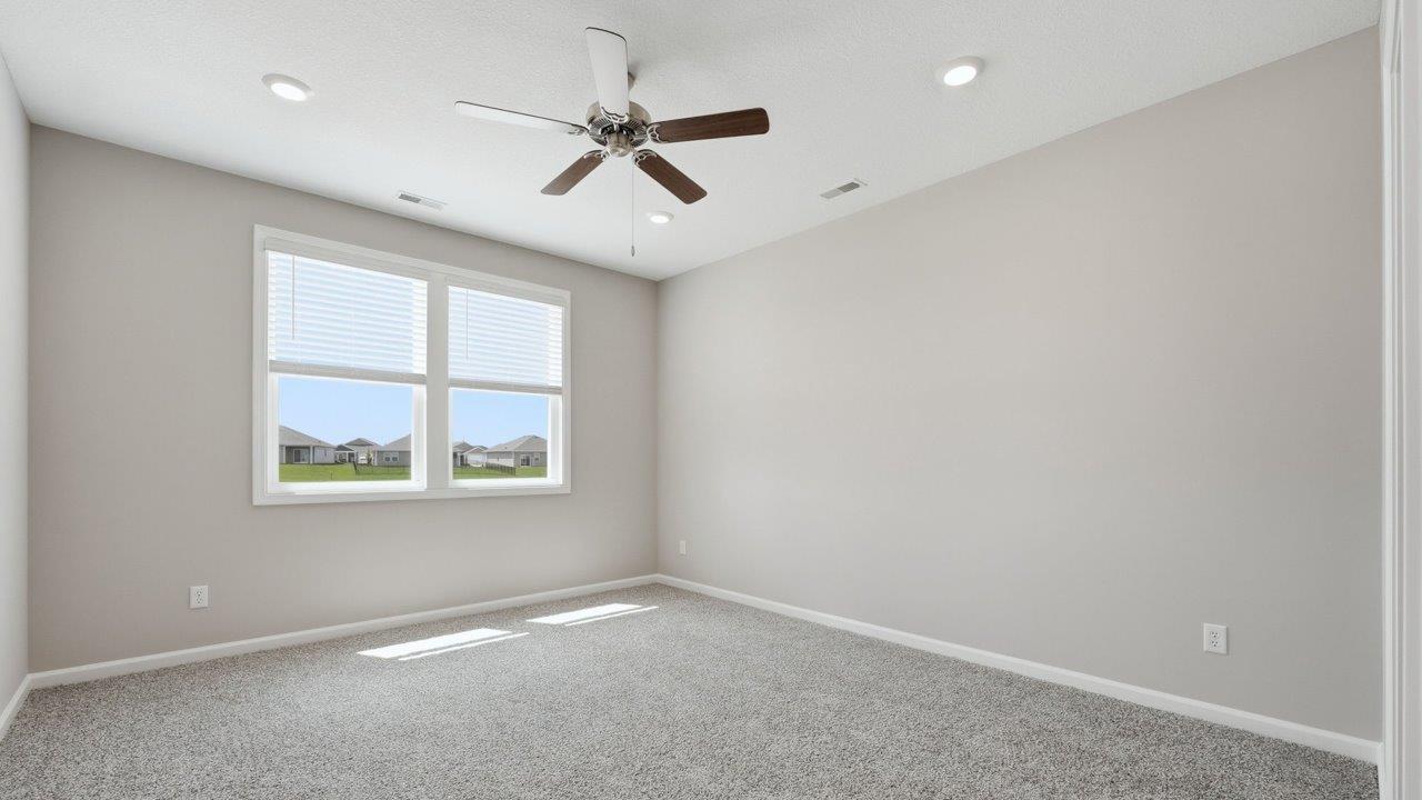 estates at signal ridge harmony villa primary bedroom with 2 windows, carpet, ceiling fan, and ensuite bathroom and closet