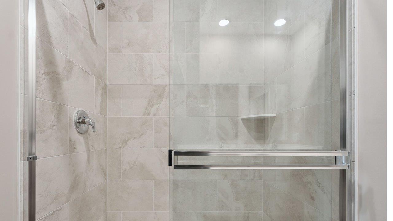 estates at signal ridge harmony villa primary bedroom ensuite bathroom with white cabinetry, lvp flooring, and ceramic tile walk-in shower
