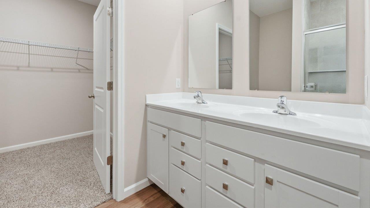 estates at signal ridge harmony villa primary bedroom ensuite bathroom with white cabinetry, lvp flooring, and ceramic tile walk-in shower