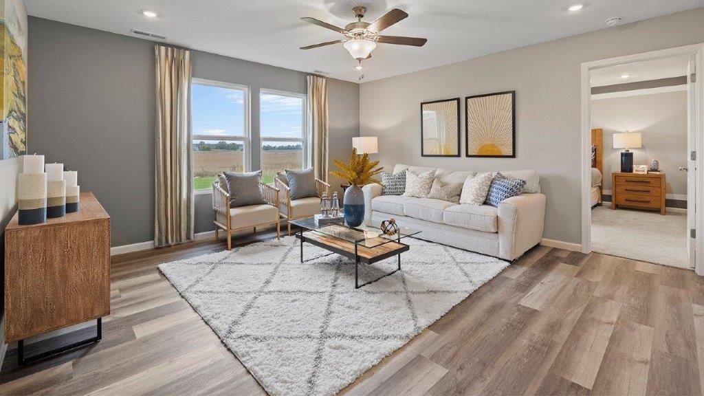 living room with lvp flooring, ceiling fan, 2 windows, and grey walls