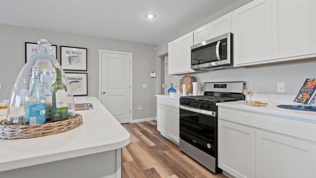 kitchen with white cabinets, stainless steel appliances, corner pantry, quartz countertops, and center island with bar seating