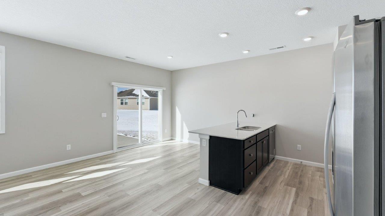 kitchen with sarsaparilla shaker cabinets, quartz counters, stainless steel appliances, ceramic tile backsplash, and island with seating