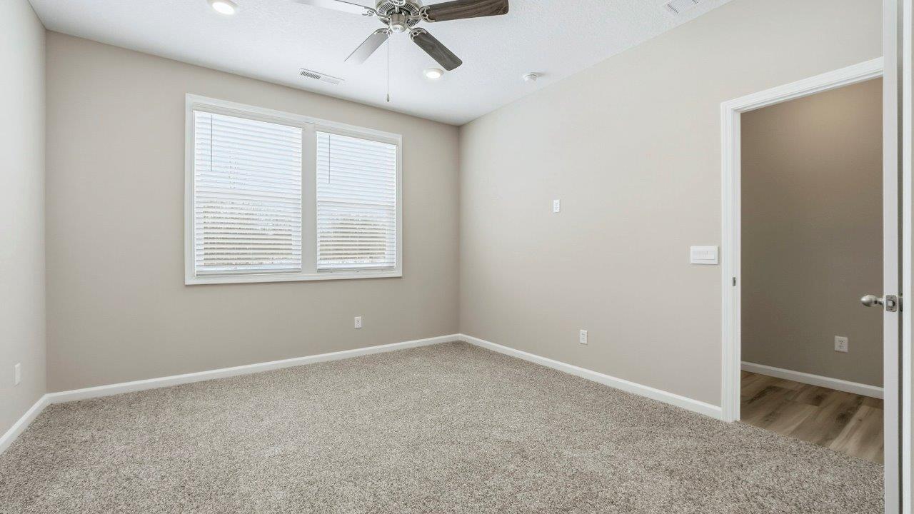 primary bedroom with carpet, fan, and ensuite bath and closet