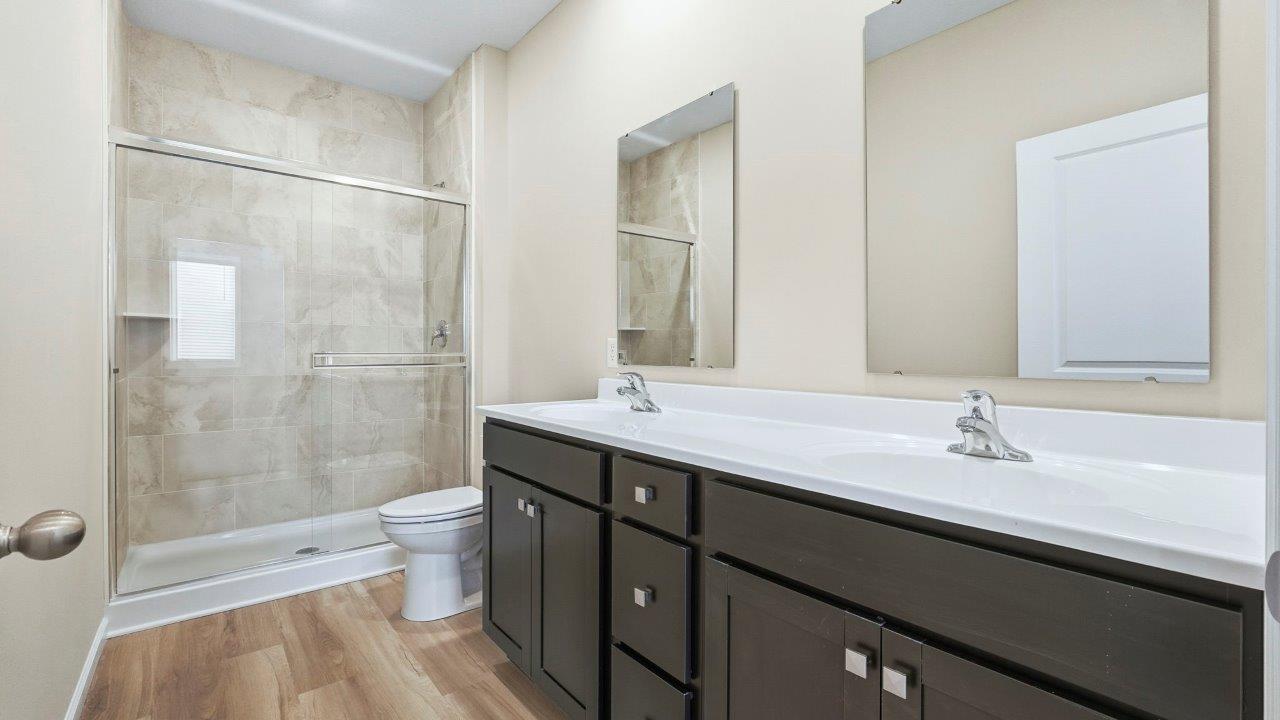 primary ensuite bathroom with dual sinks and ceramic tile shower